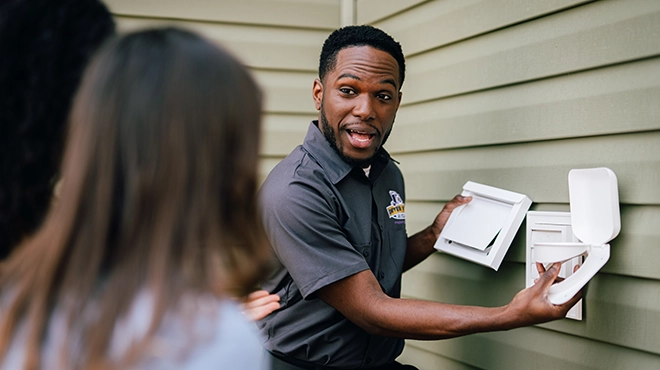 Technician with customers holding vent cover.