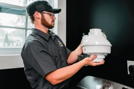 A Dryer Vent Wizard pro installing a residential booster fan in home.