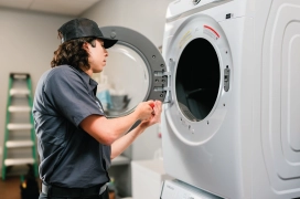 Dryer Vent Wizard professional making adjustments to commercial dryer door.